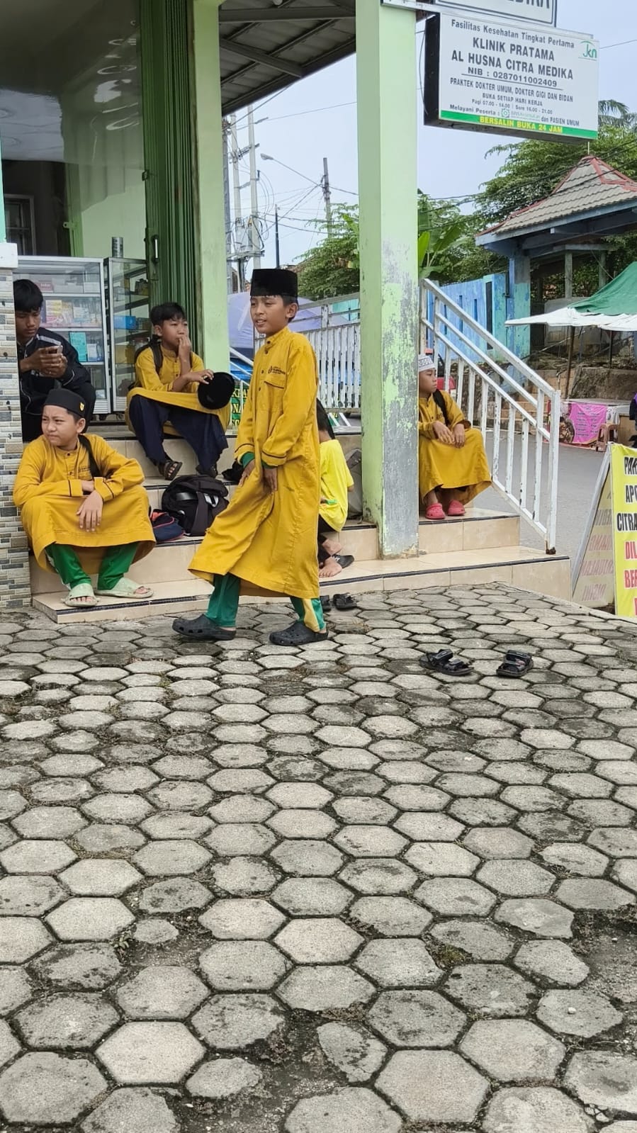 Santri GHQ duduk di luar gedung di depan klinik